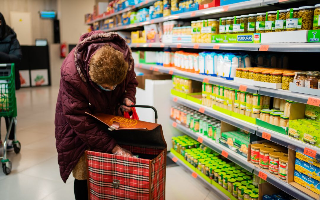 Lady placing groceries in wheely trolley at supermarket