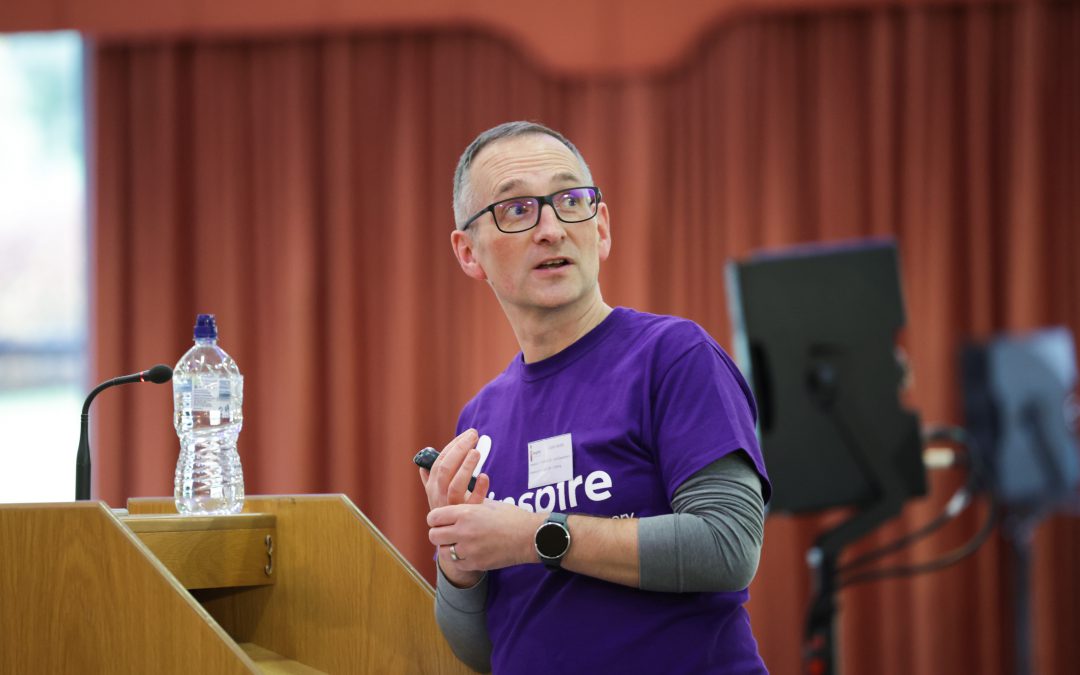 Colin Smith presenting from a podium at Inspire's 2022 staff and volunteer conference