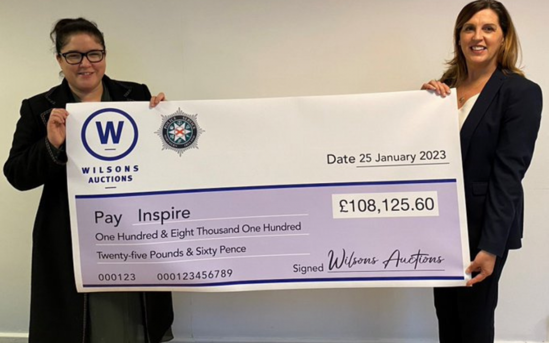 Inspire CEO Kerry Anthony and a representative from Wilson's Auction House holding a cheque for £108,125.60